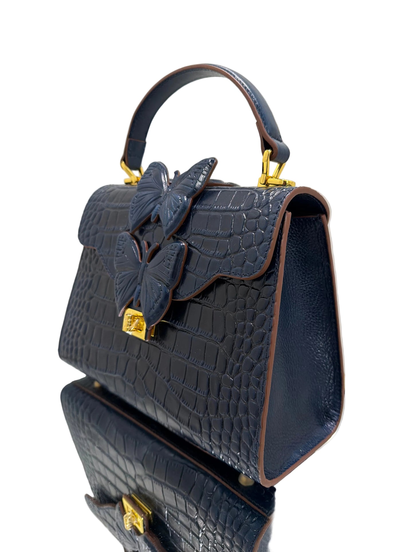 Dark blue textured handbag with butterfly design and gold accents on a light background