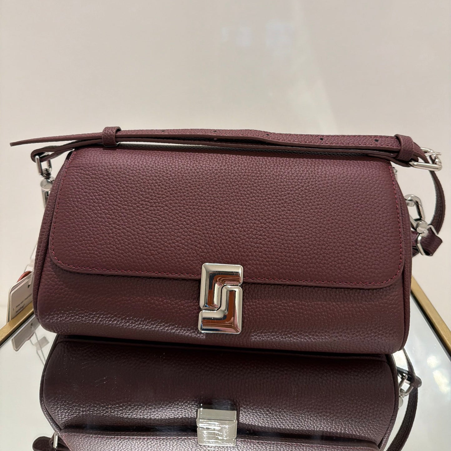 Two brown leather handbags with silver buckles on a light gray background