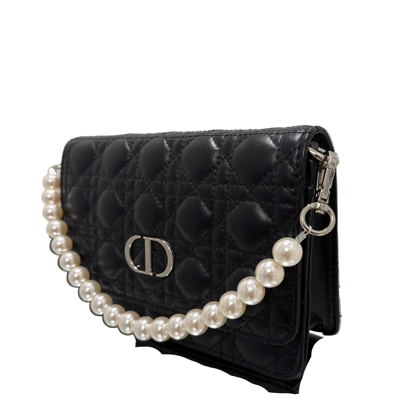 Black quilted handbag with a pearl necklace draped over it on a white background
