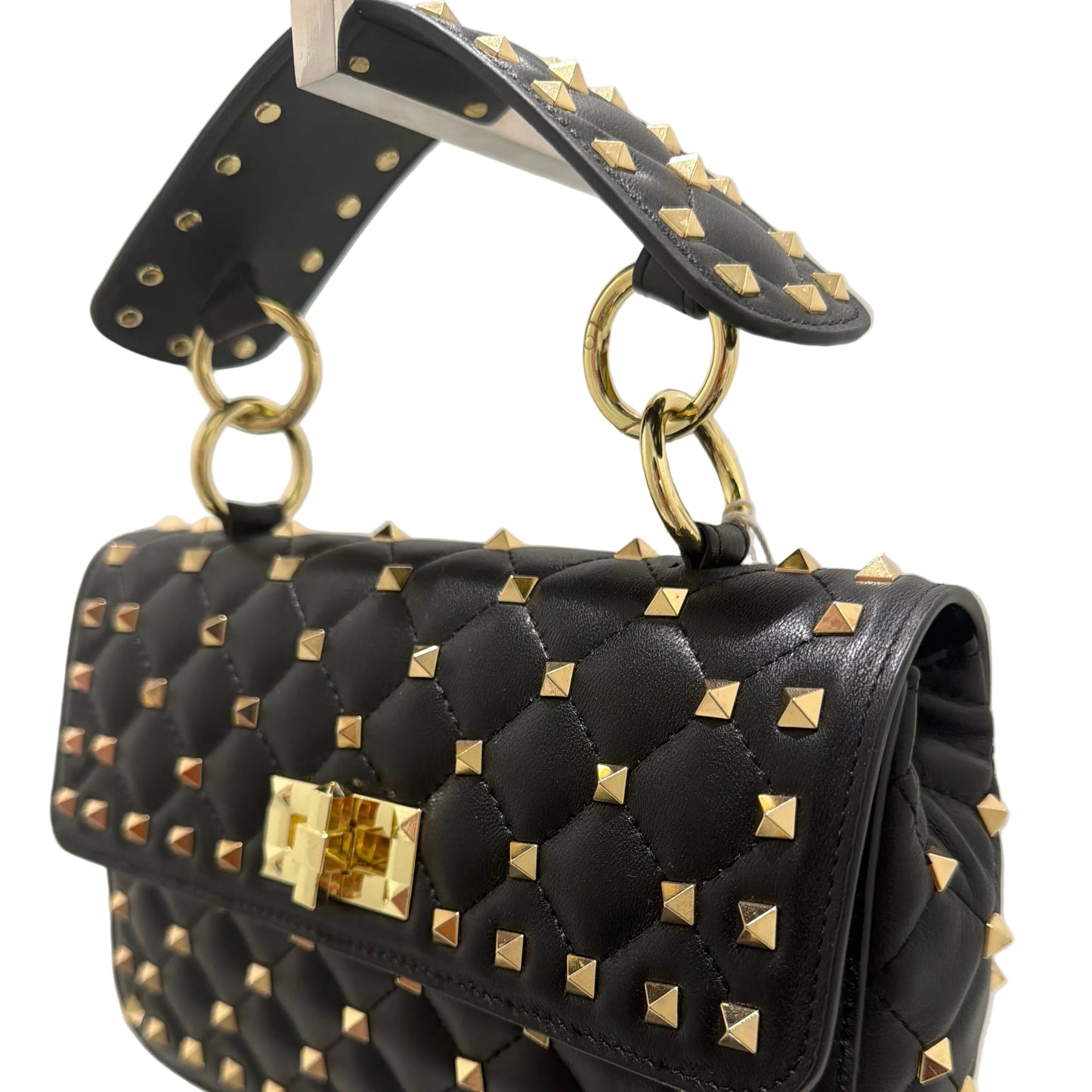 Black studded handbag with gold accents on a light gray background