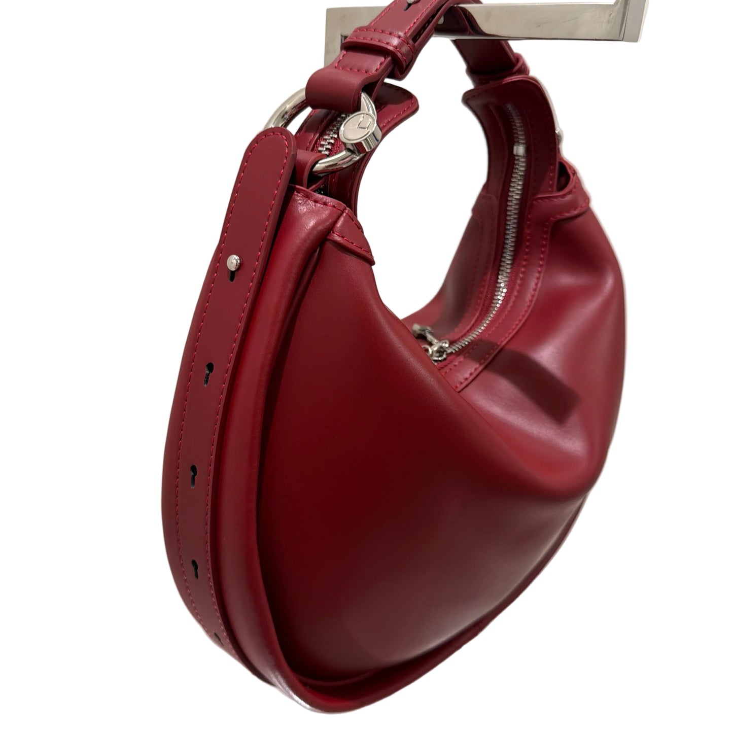 Red leather dog muzzle on a white surface with a mirror reflection.