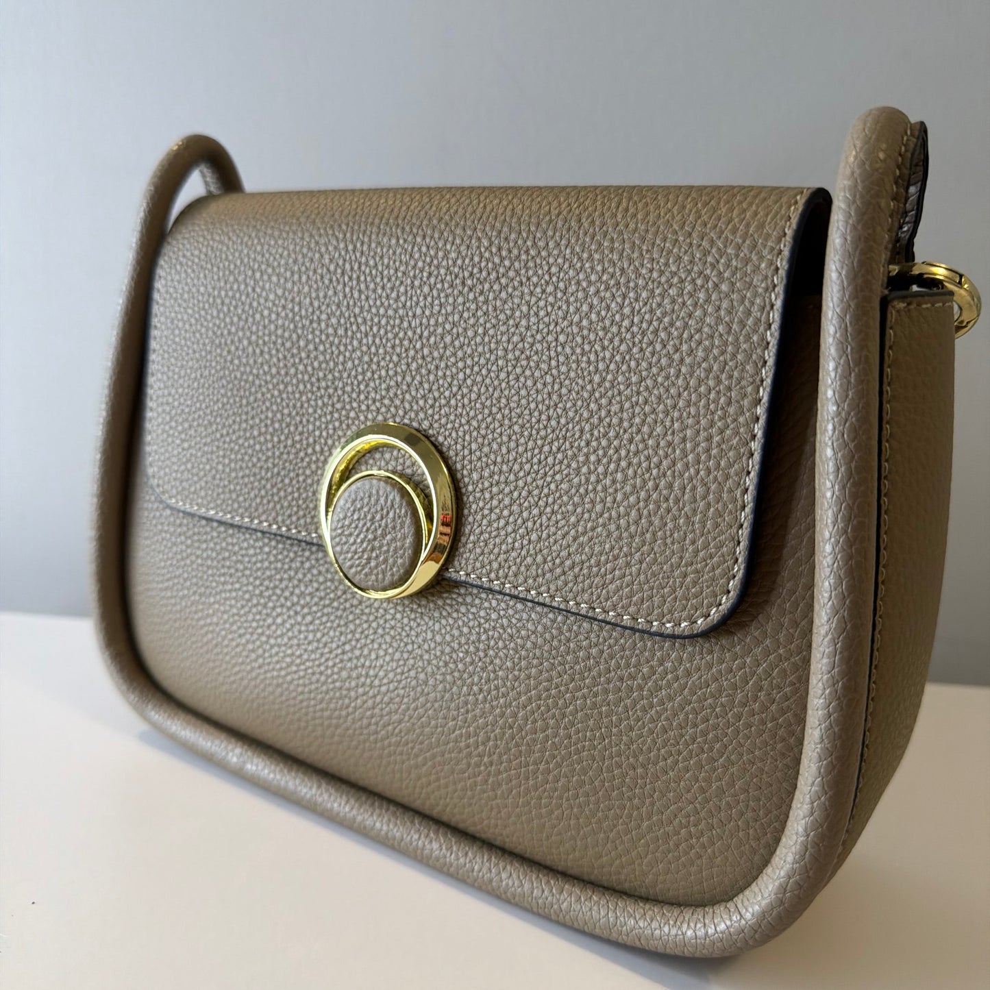 Beige handbag with a gold clasp on a light background