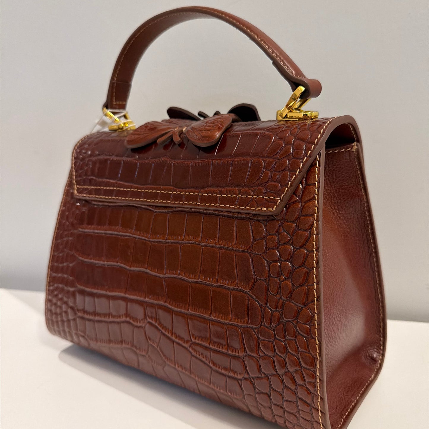 Brown textured handbag with a handle on a light gray background