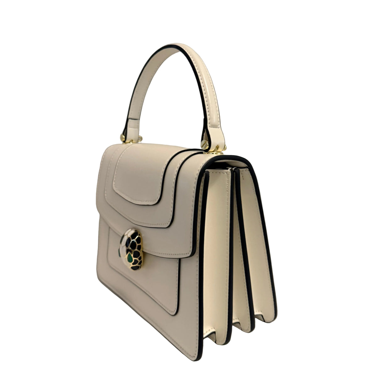 A structured white leather handbag with black piping, a top handle, and a decorative gold-tone clasp, photographed on a plain light gray background.
