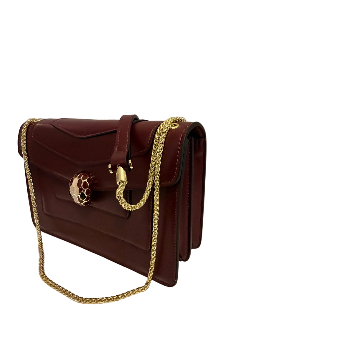 A dark burgundy leather shoulder bag with a gold chain strap and a distinctive gold snake-head clasp, displayed on a white surface against a neutral gray background.