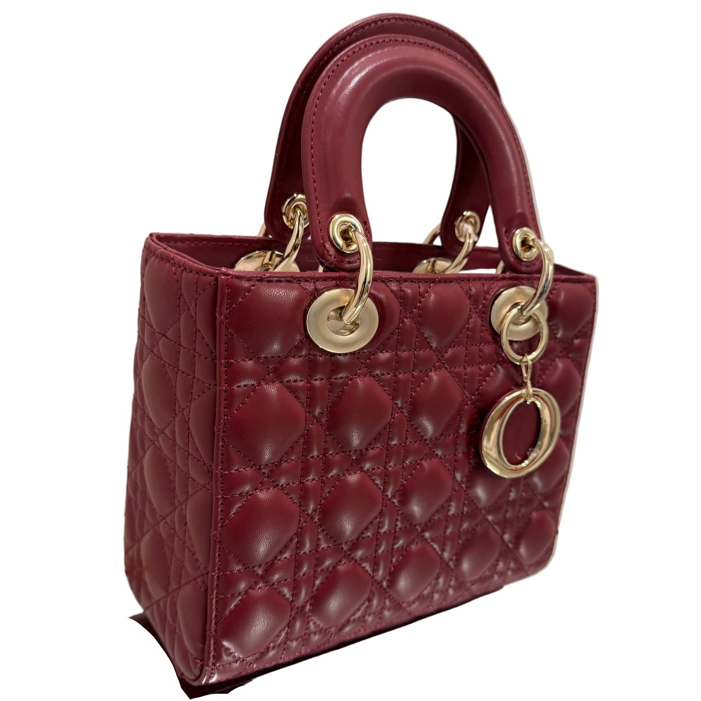 Maroon handbag with gold hardware on a reflective surface