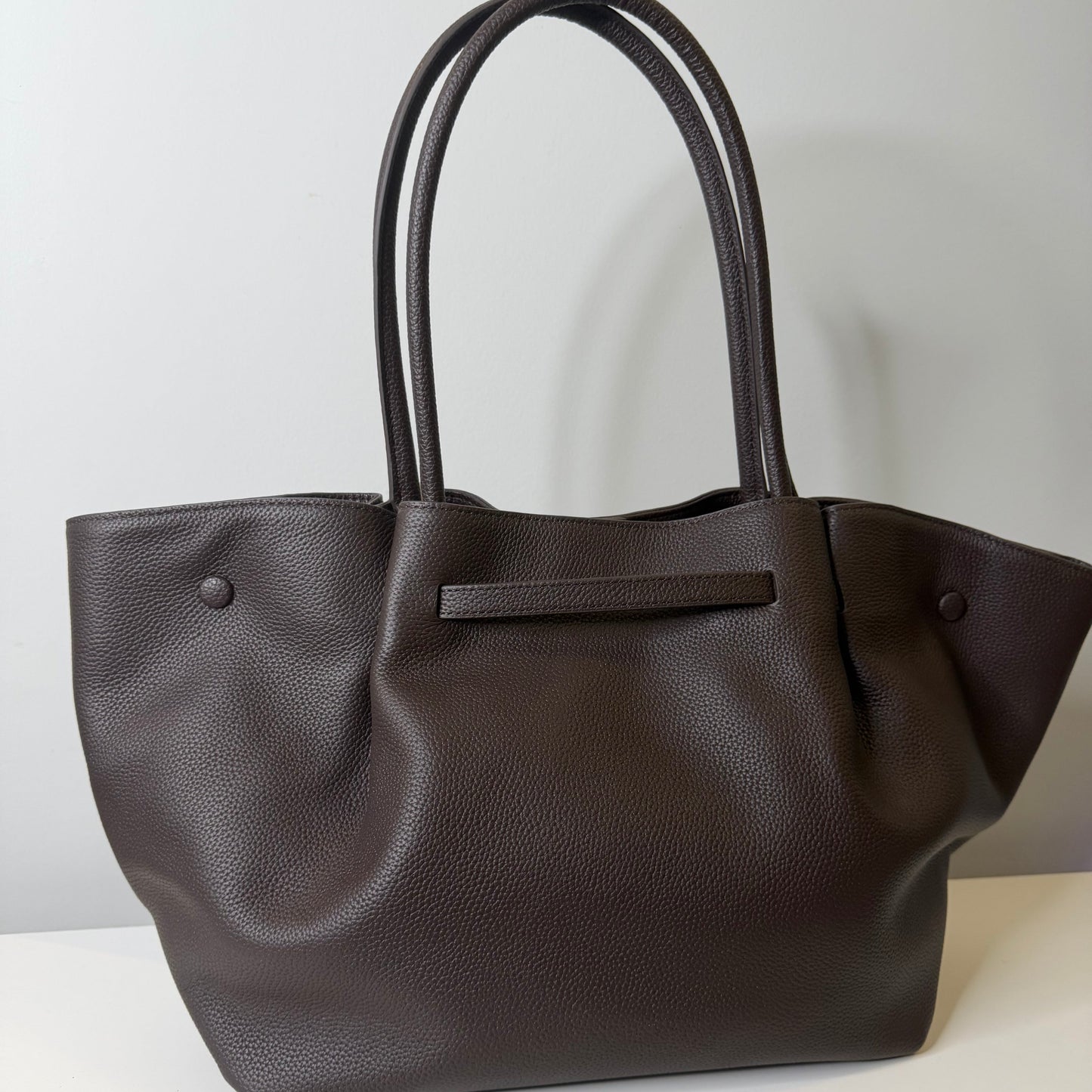 Dark brown leather tote bag on a light gray background