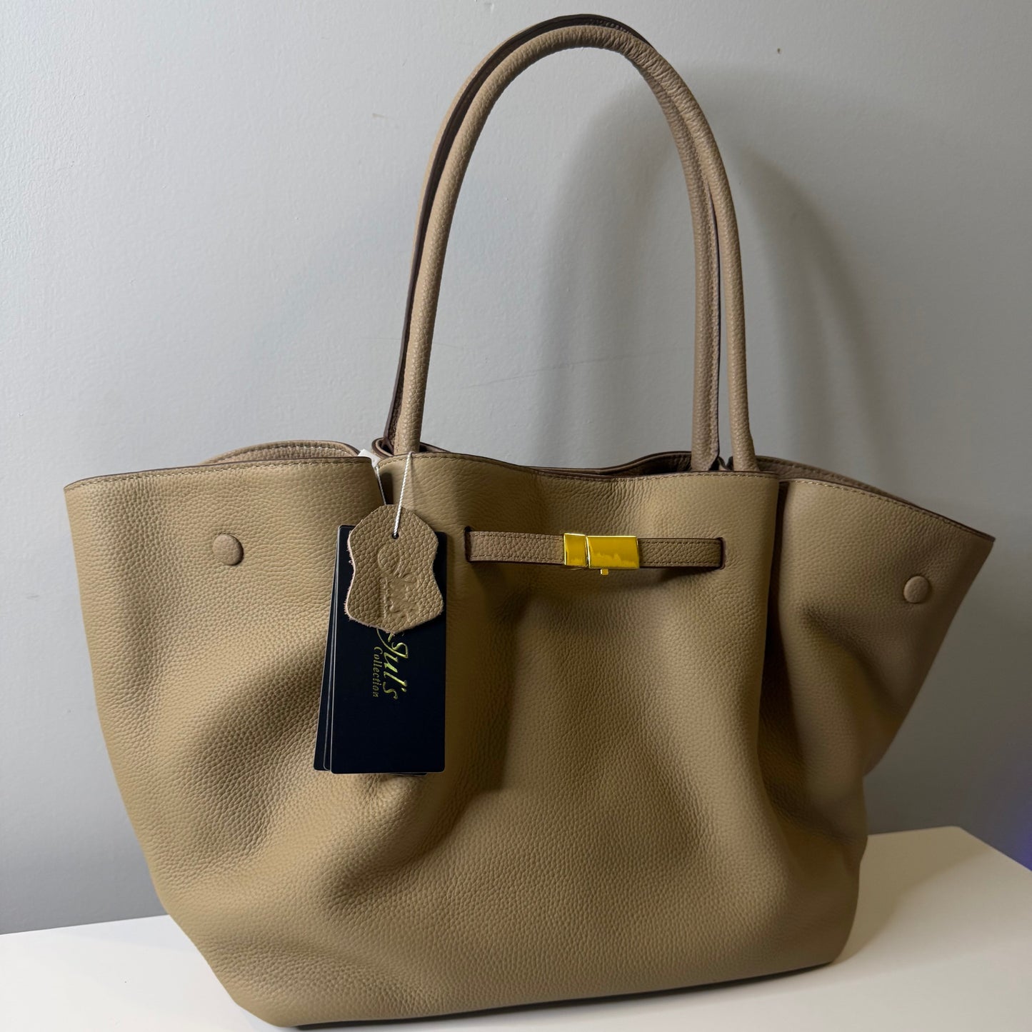 Beige handbag with a visible brand tag on a white background