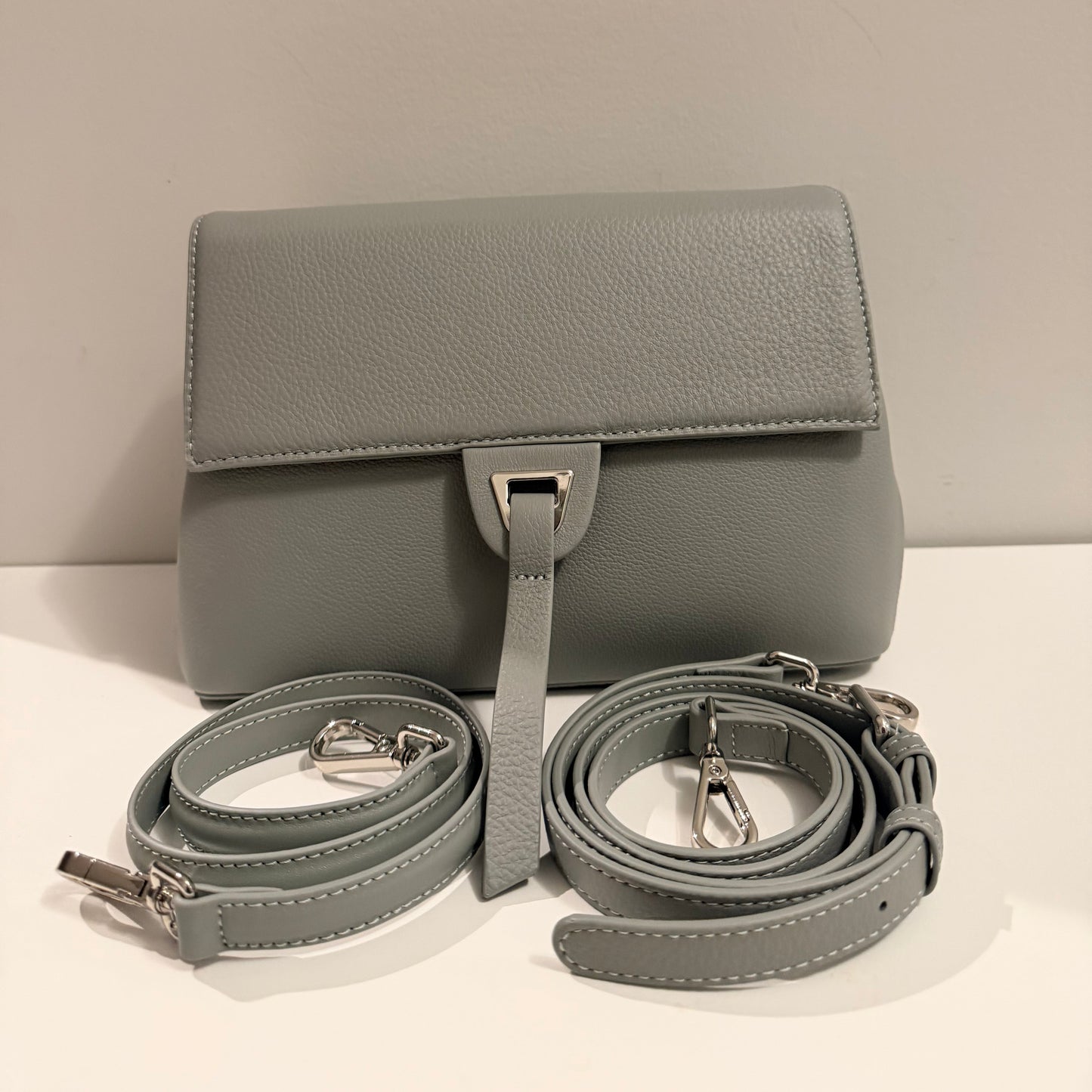 Gray handbag with matching strap on a light beige background