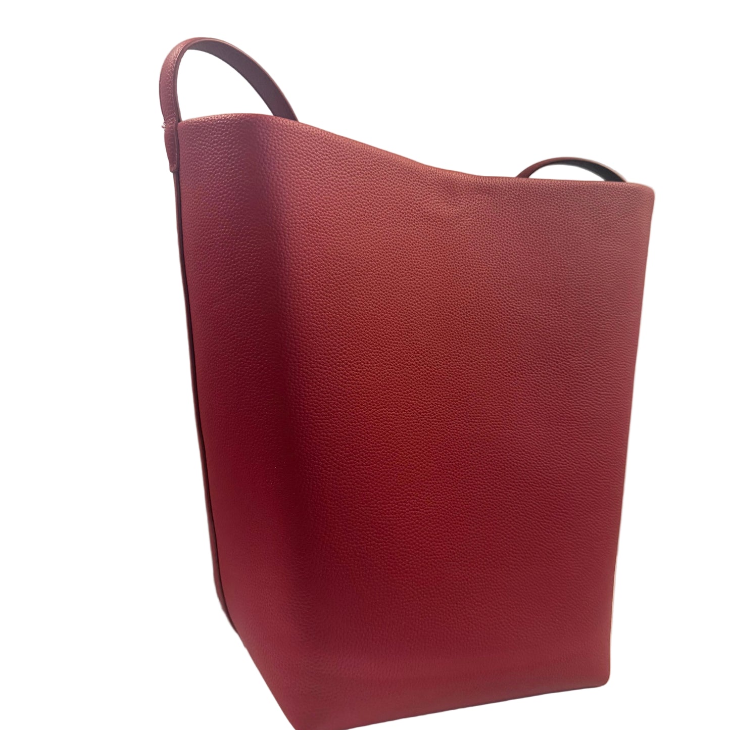 Red leather tote bag on a light gray surface with a neutral background