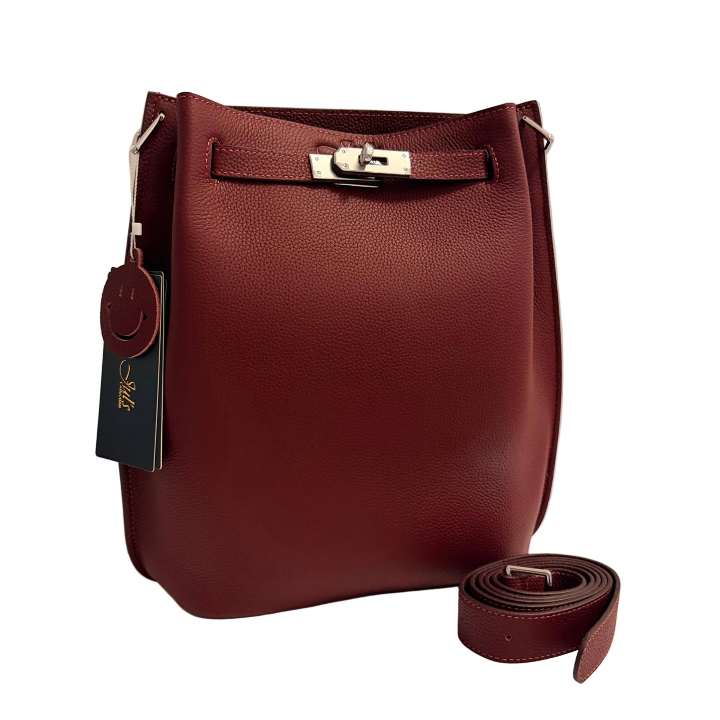 A burgundy pebbled leather bucket bag with a silver-tone turn-lock closure and a matching detachable shoulder strap, displayed on a white surface against a light gray background. A dark green brand tag hangs from the side.