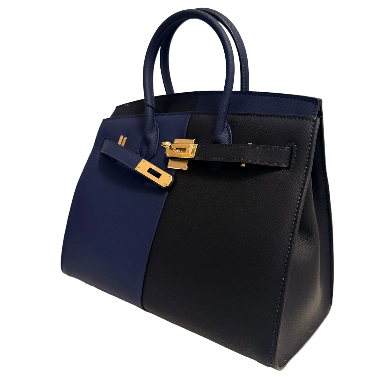A structured leather handbag in dark navy and royal blue color-blocked panels with gold-tone hardware, photographed on a clean white surface against a light neutral background.