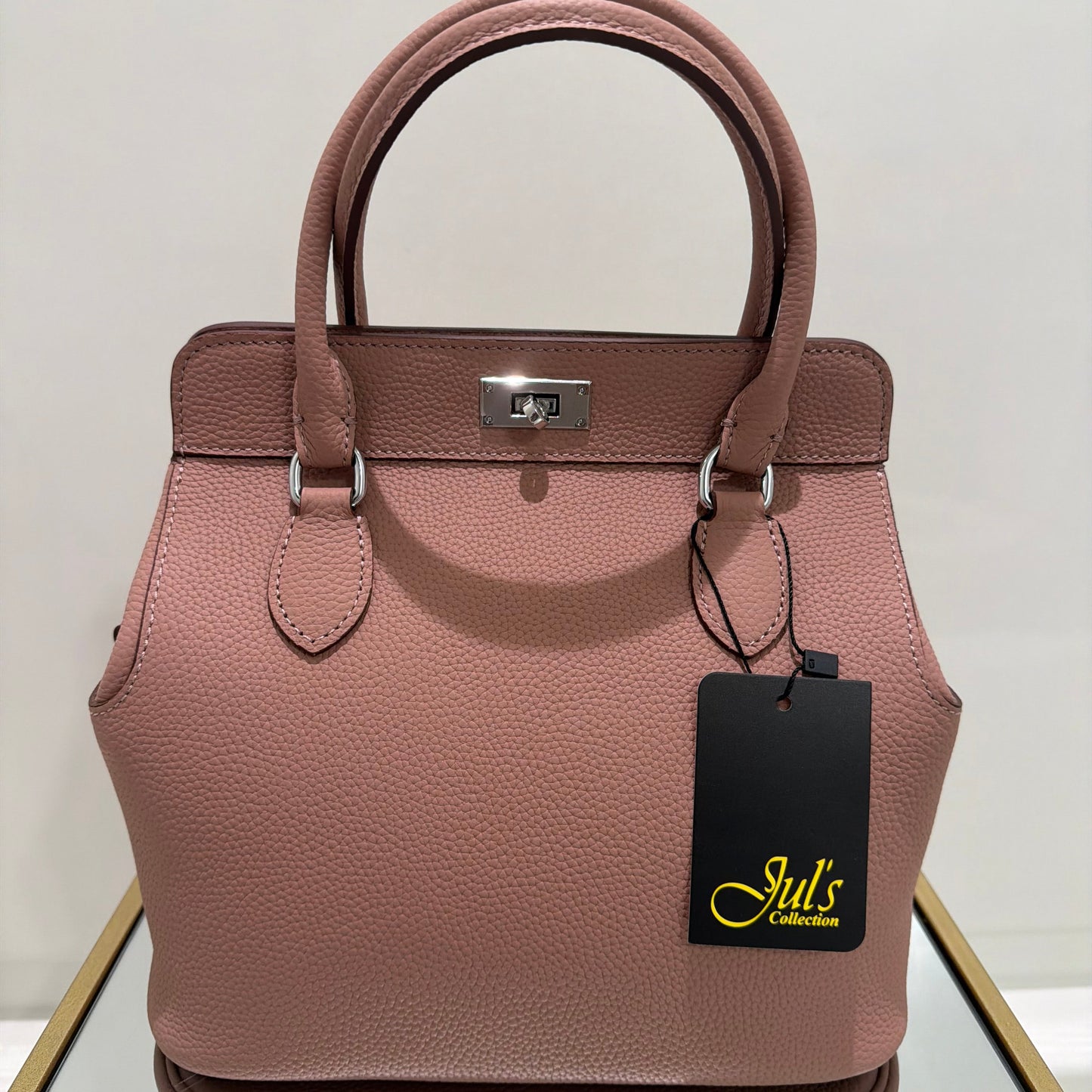 Pink handbag with a visible brand tag on a light background