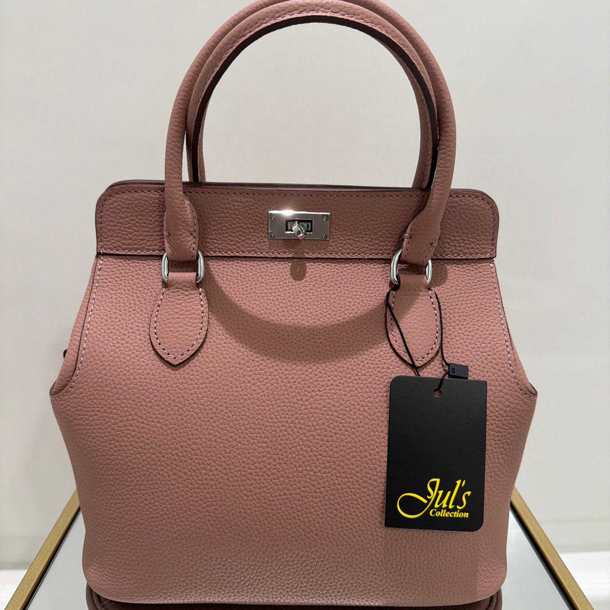Pink handbag with a visible brand tag on a light background