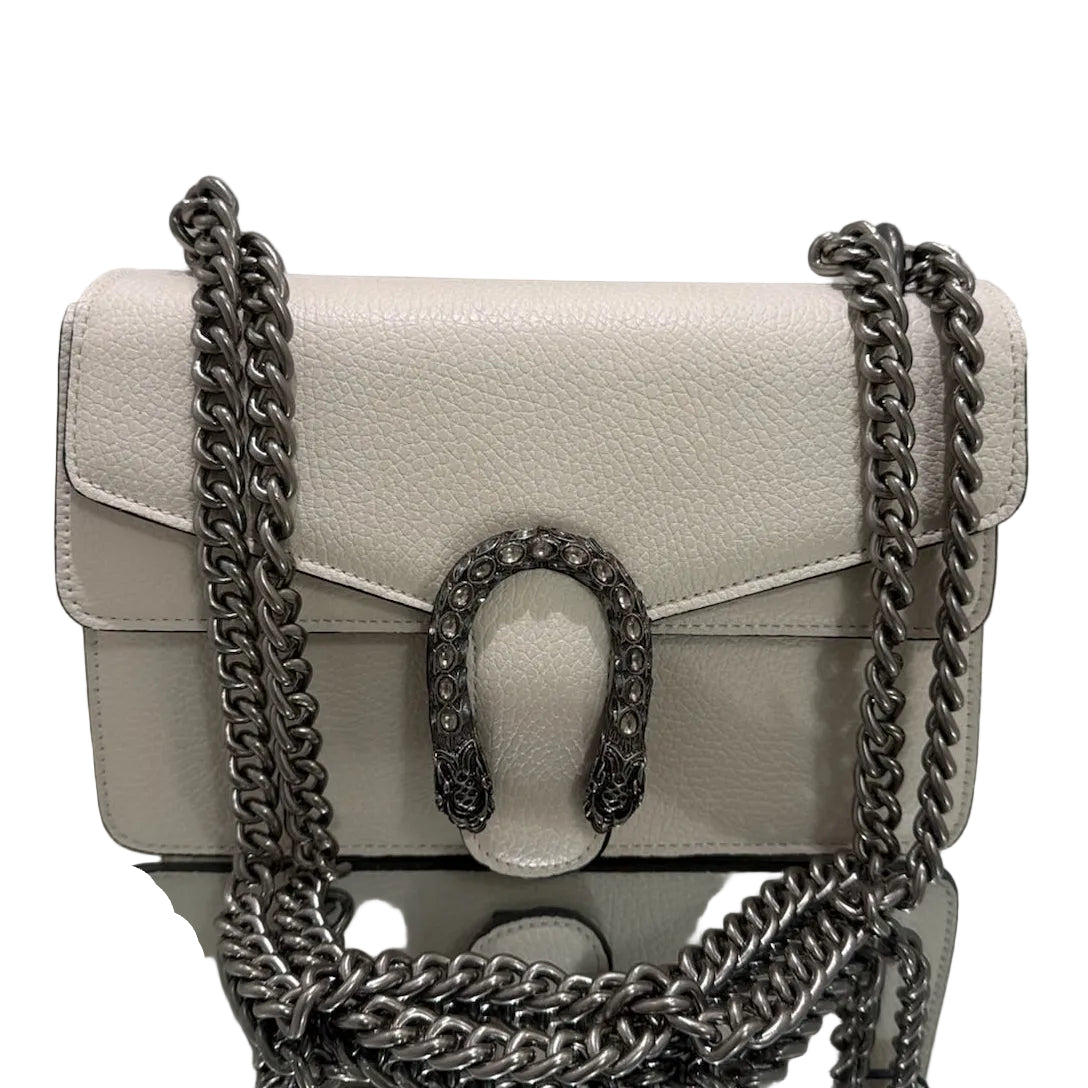 White handbag with silver chain strap on a reflective surface