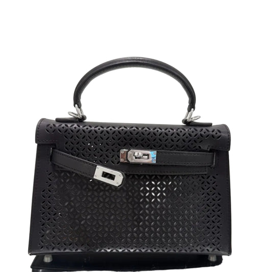 Black handbag with intricate design on a reflective surface