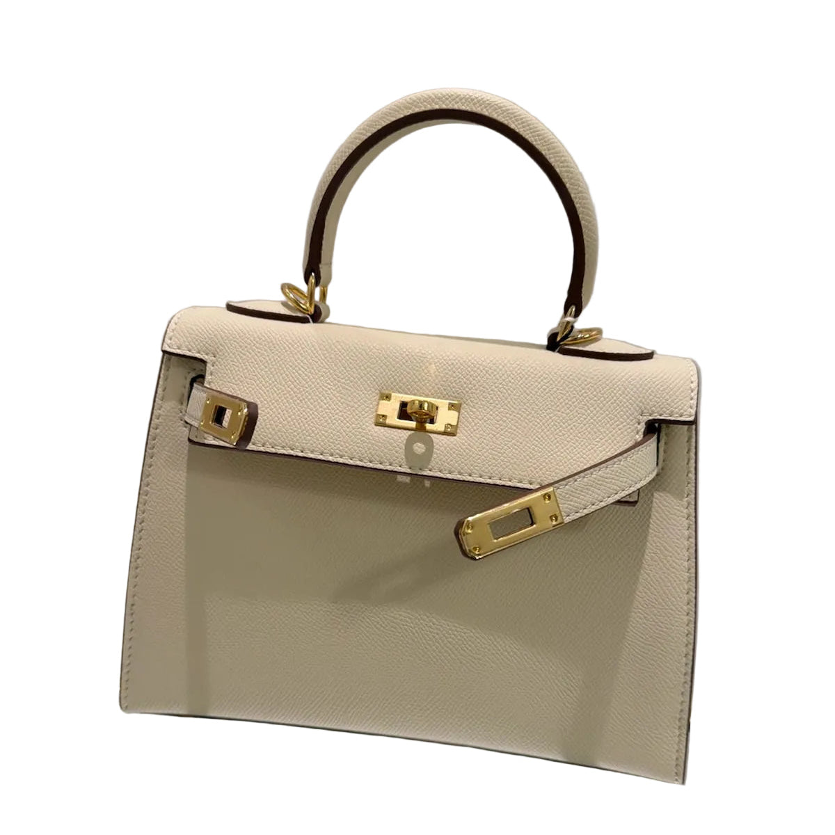 Beige handbag with gold hardware on a reflective surface