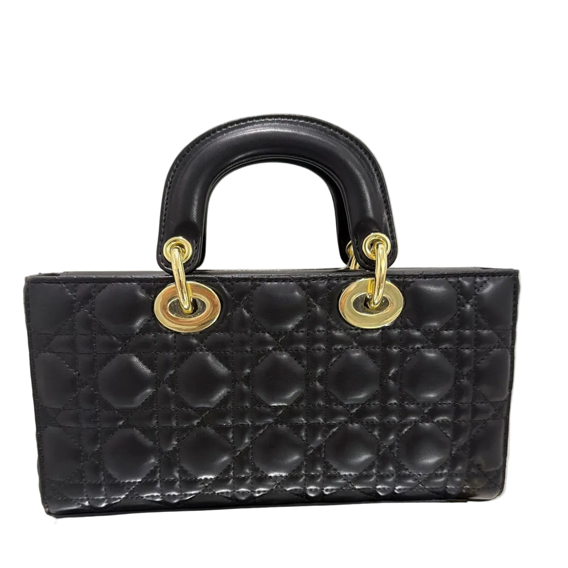 Black quilted handbag with gold hardware on a light gray background