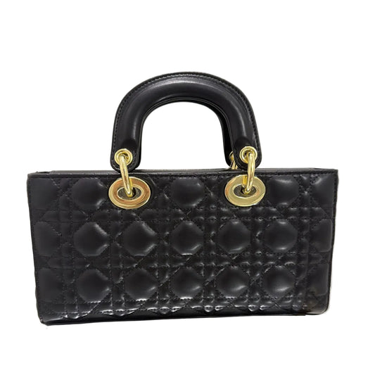 Black quilted handbag with gold hardware on a light gray background
