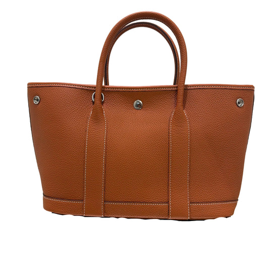 Brown leather handbag with visible stitching on a white background