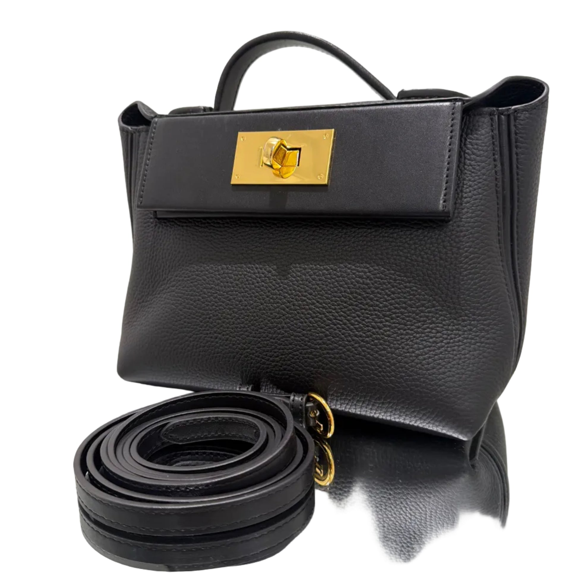 Black leather handbag with gold accents on a reflective surface