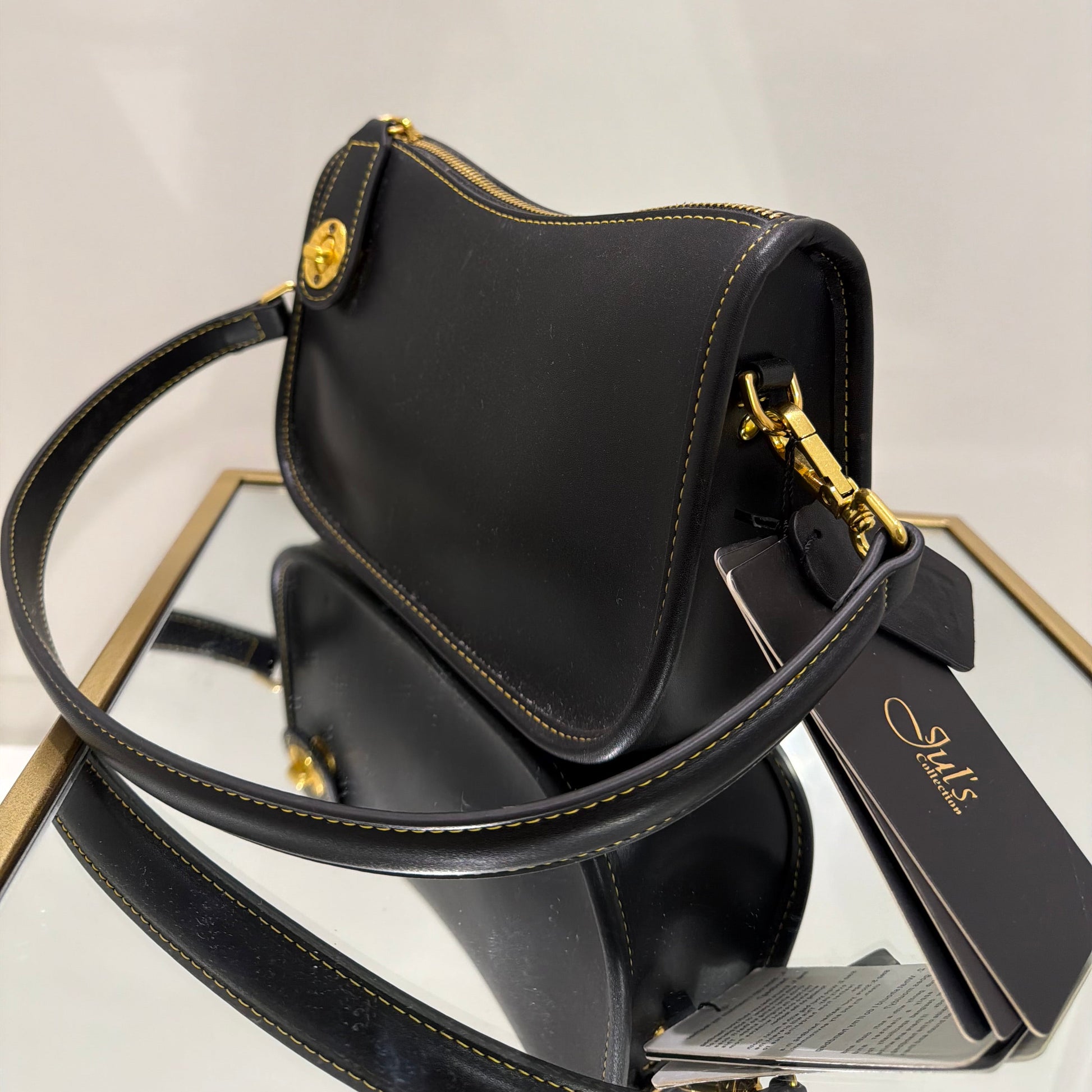 Black handbag with gold accents on a light gray background
