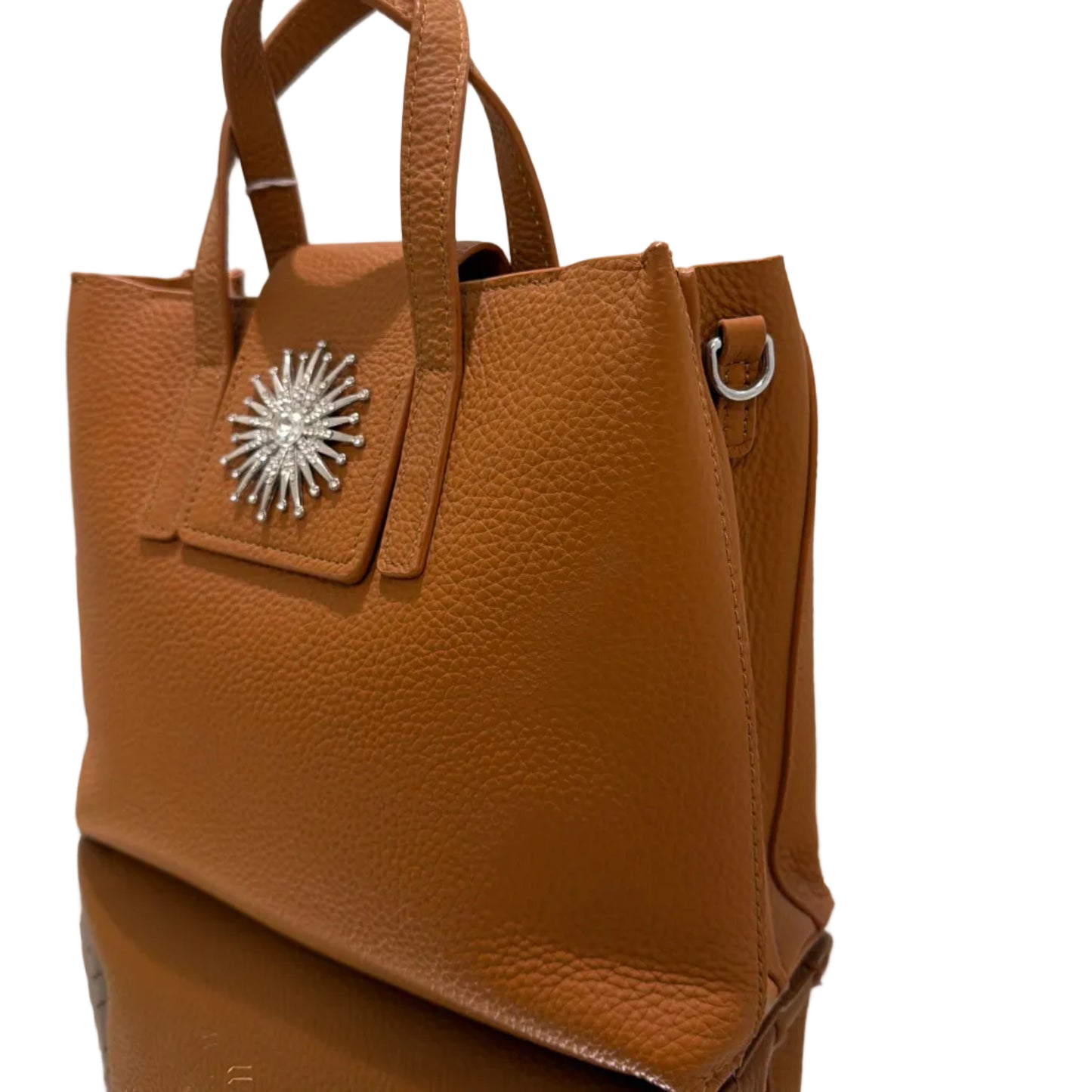 Brown leather handbag with a decorative starburst emblem on a white background