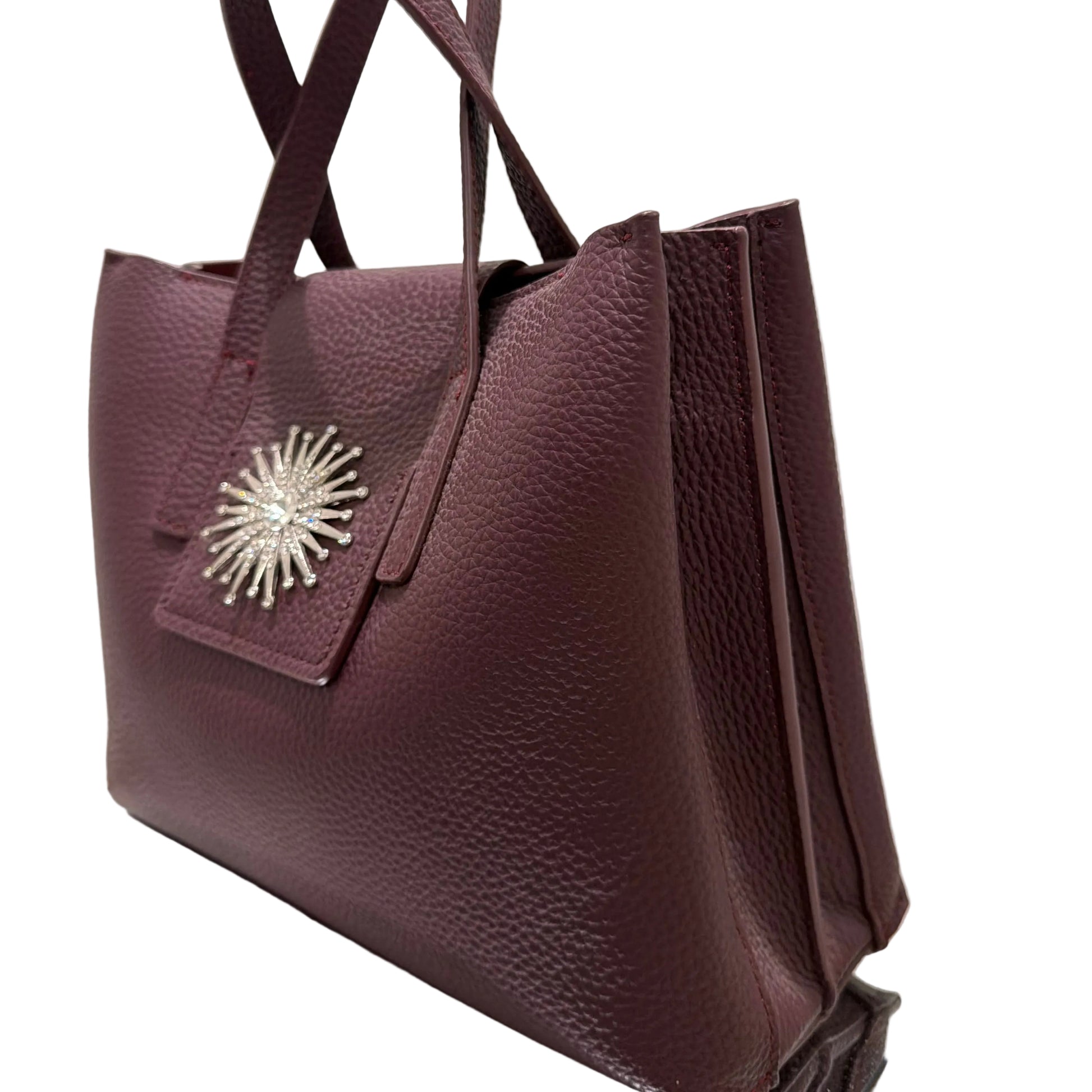 Purple handbag with a decorative emblem on a light background