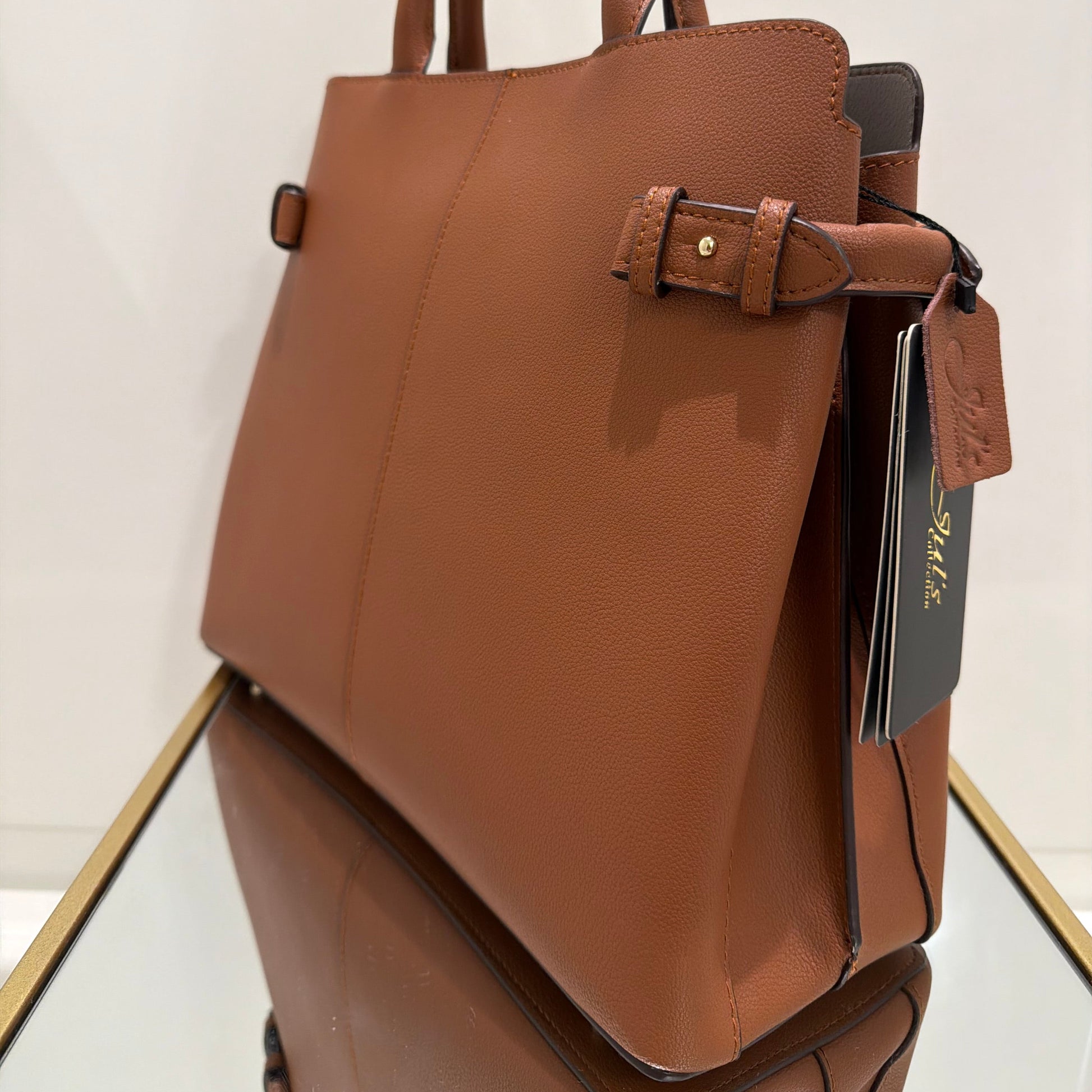 Brown leather handbag with a strap on a white surface