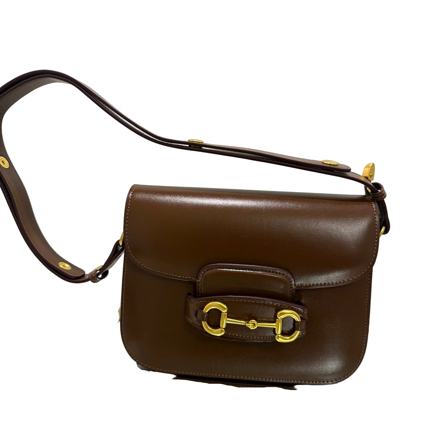 Brown leather handbag with gold hardware on a light gray background
