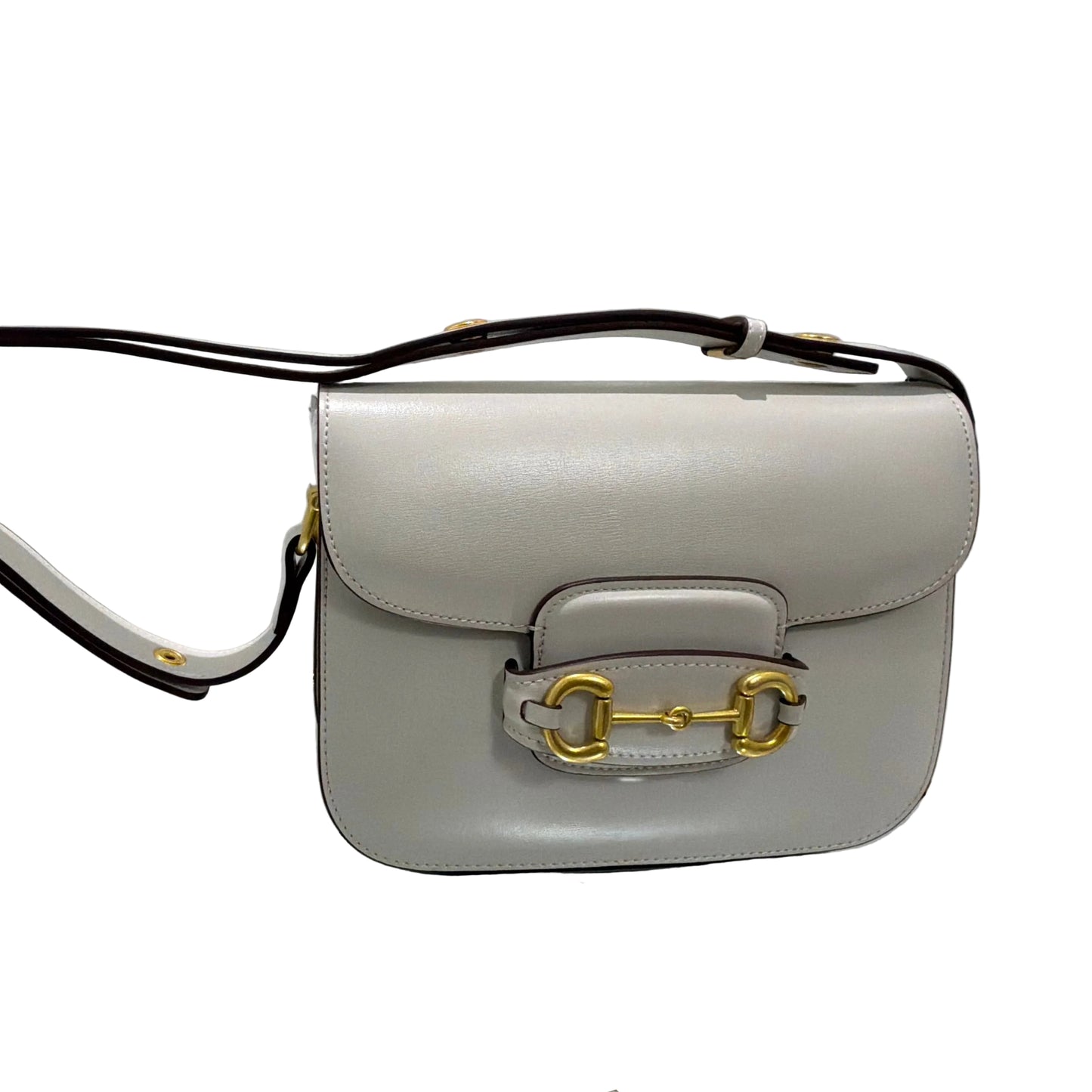 Light gray handbag with gold hardware on a white background
