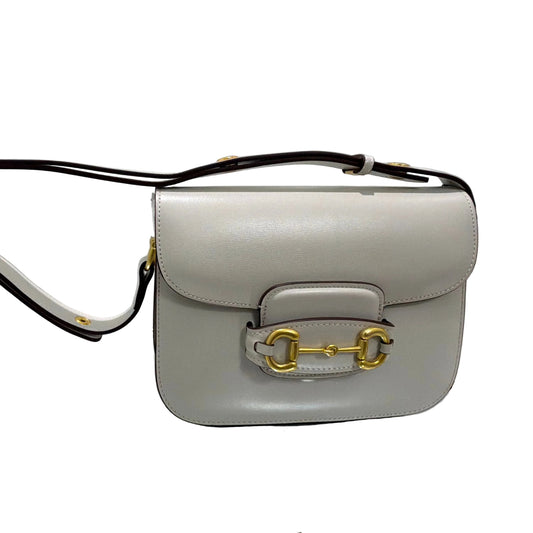 Light gray handbag with gold hardware on a white background