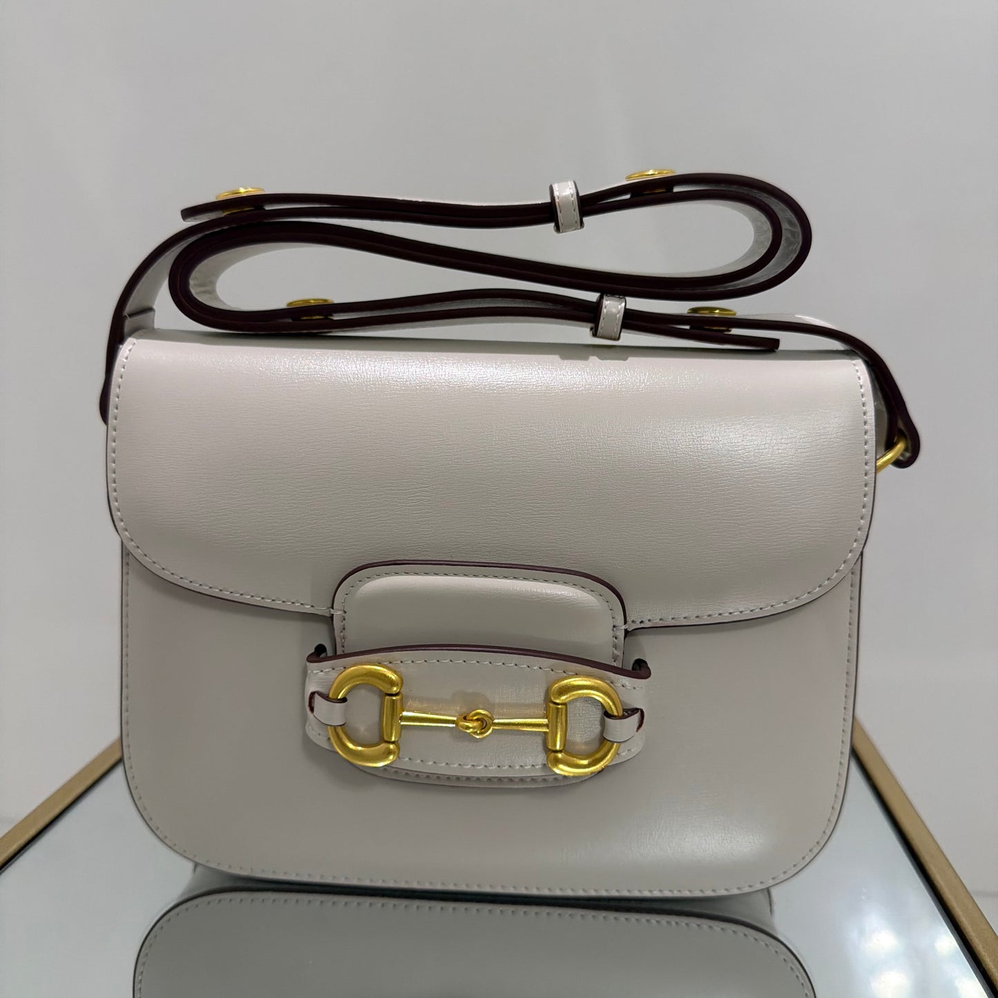 Light gray handbag with gold clasp on a white background