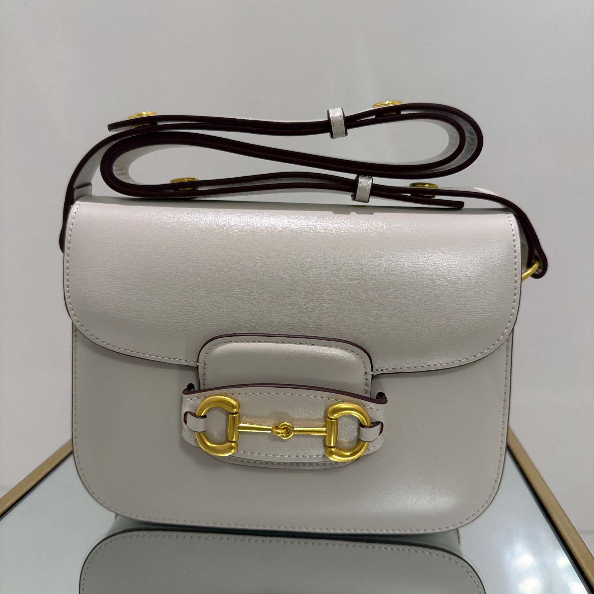 Light gray handbag with gold clasp on a white background