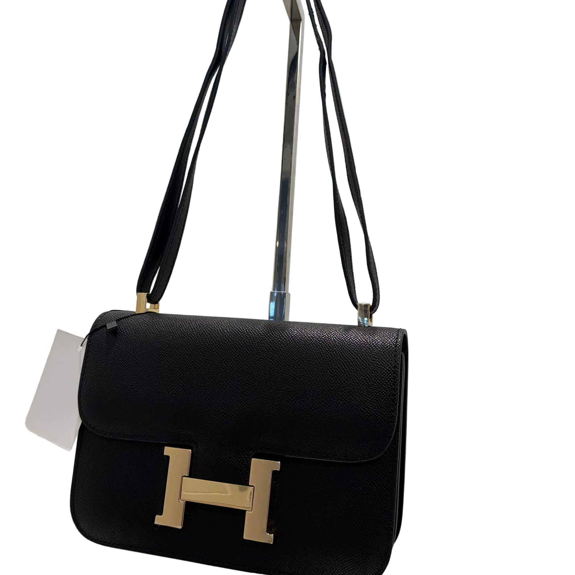 Black handbag with gold 'H' logo on a white background