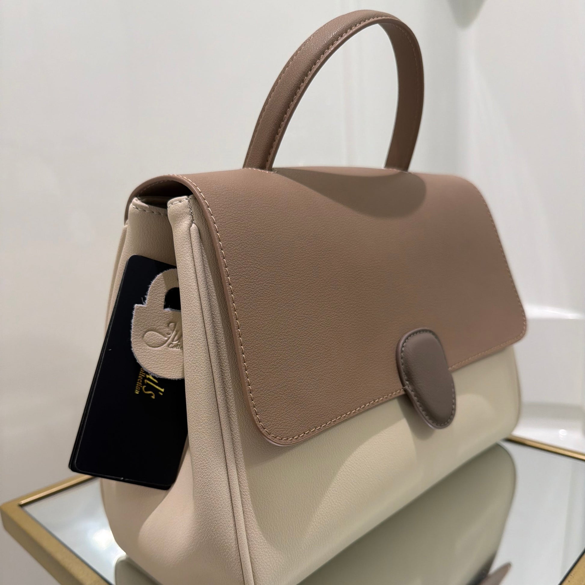 Two handbags, one beige and one brown, on a reflective surface.