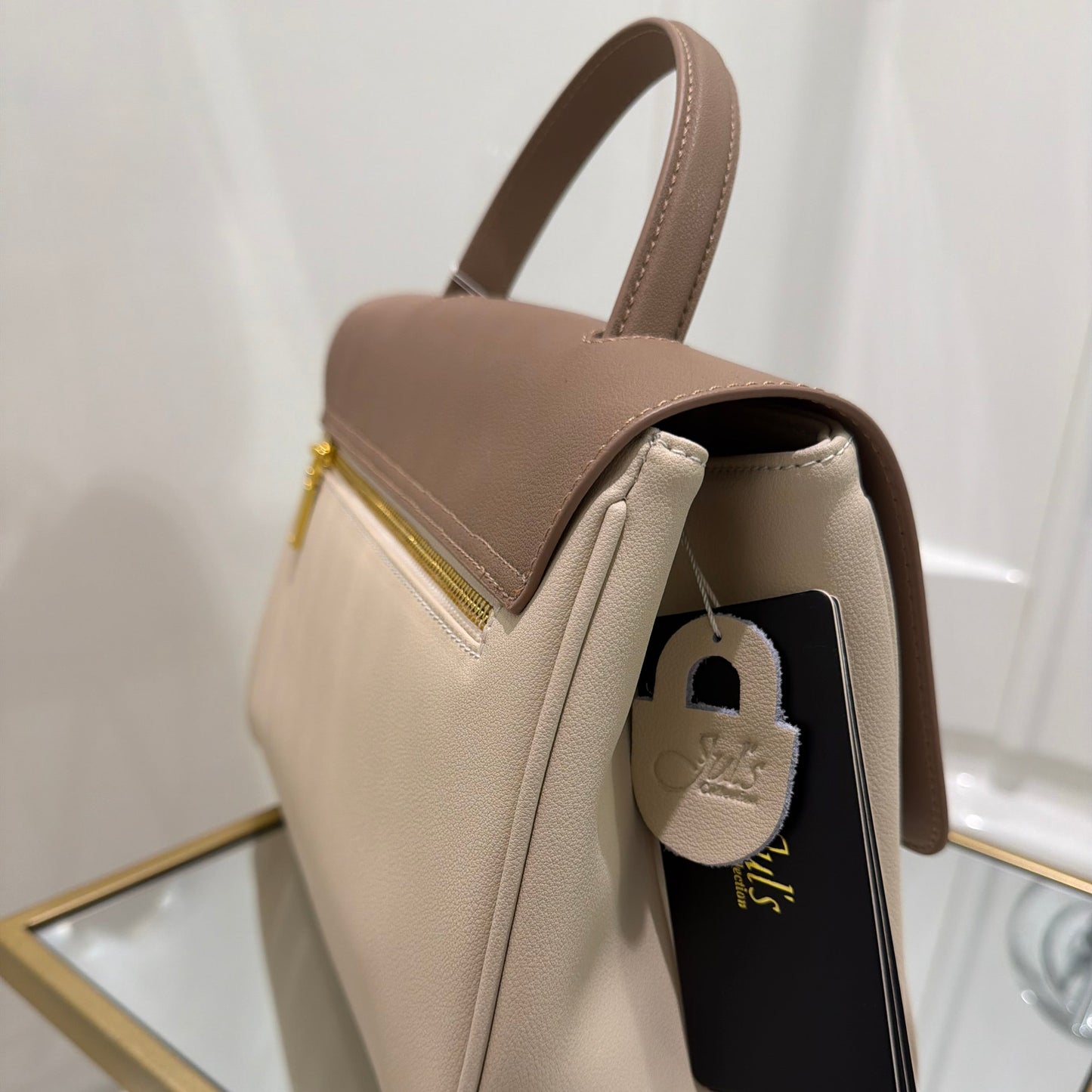 Beige handbag with a card inside on a white surface