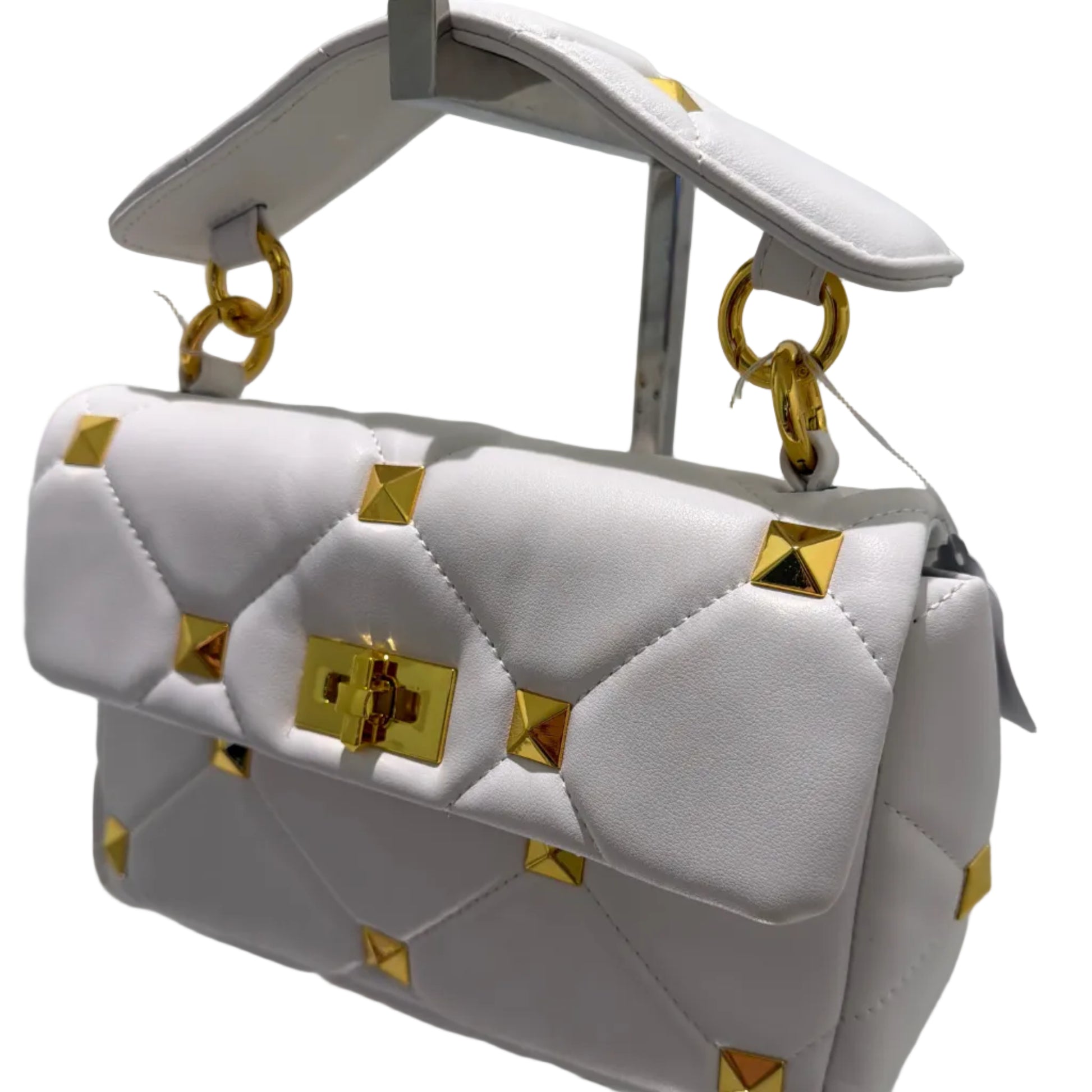 White handbag with gold accents on a reflective surface