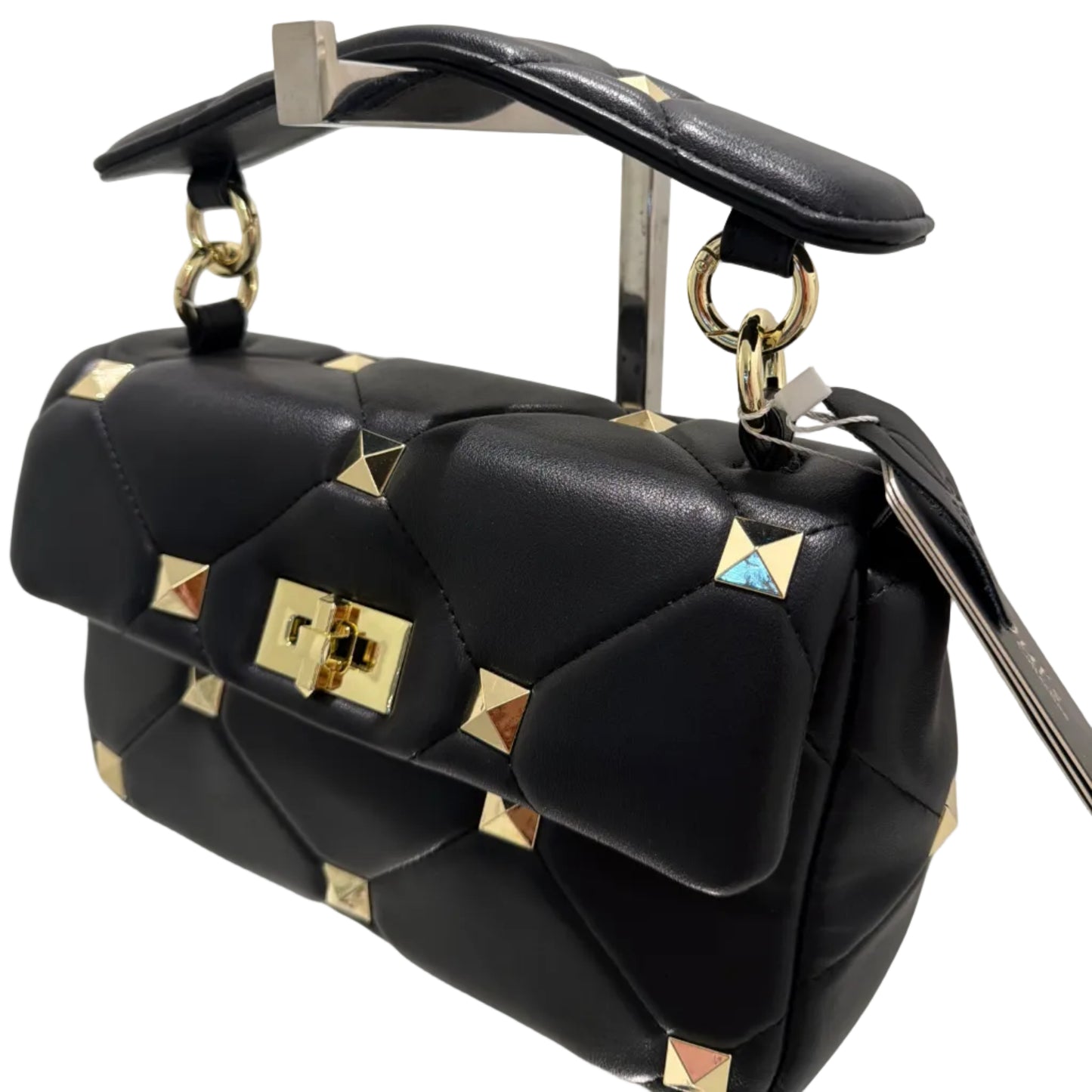 Black leather bag with gold studs and accents on a reflective surface