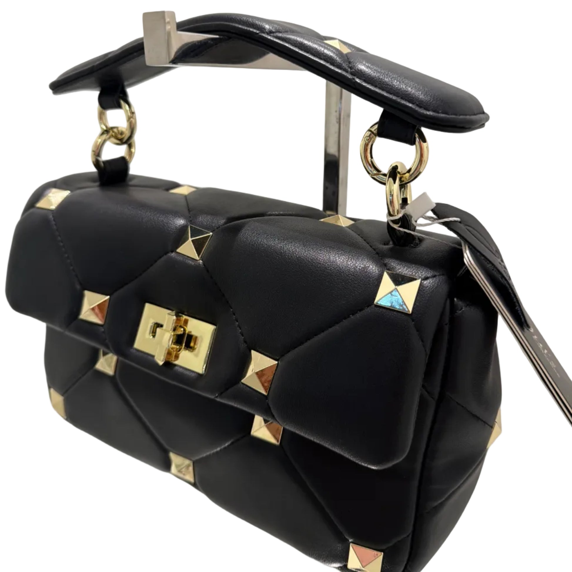 Black leather bag with gold studs and accents on a reflective surface