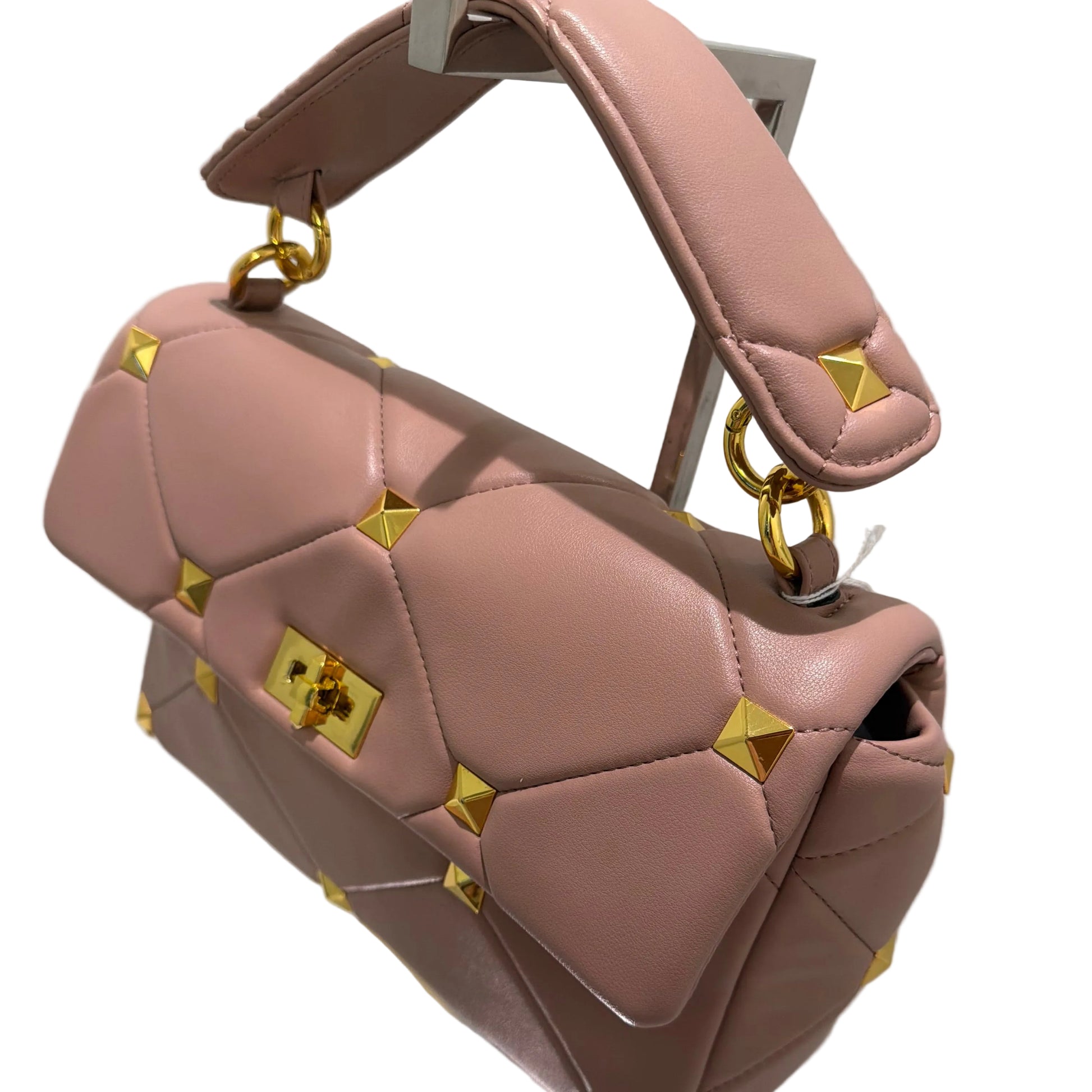 Pink handbag with gold accents on a reflective surface