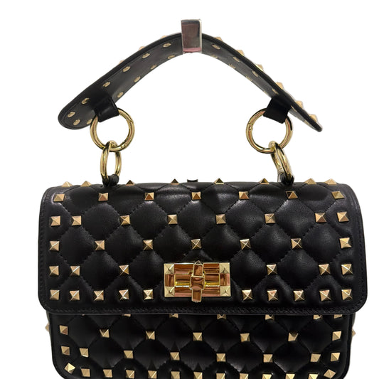 Black studded handbag with gold accents on a light gray background
