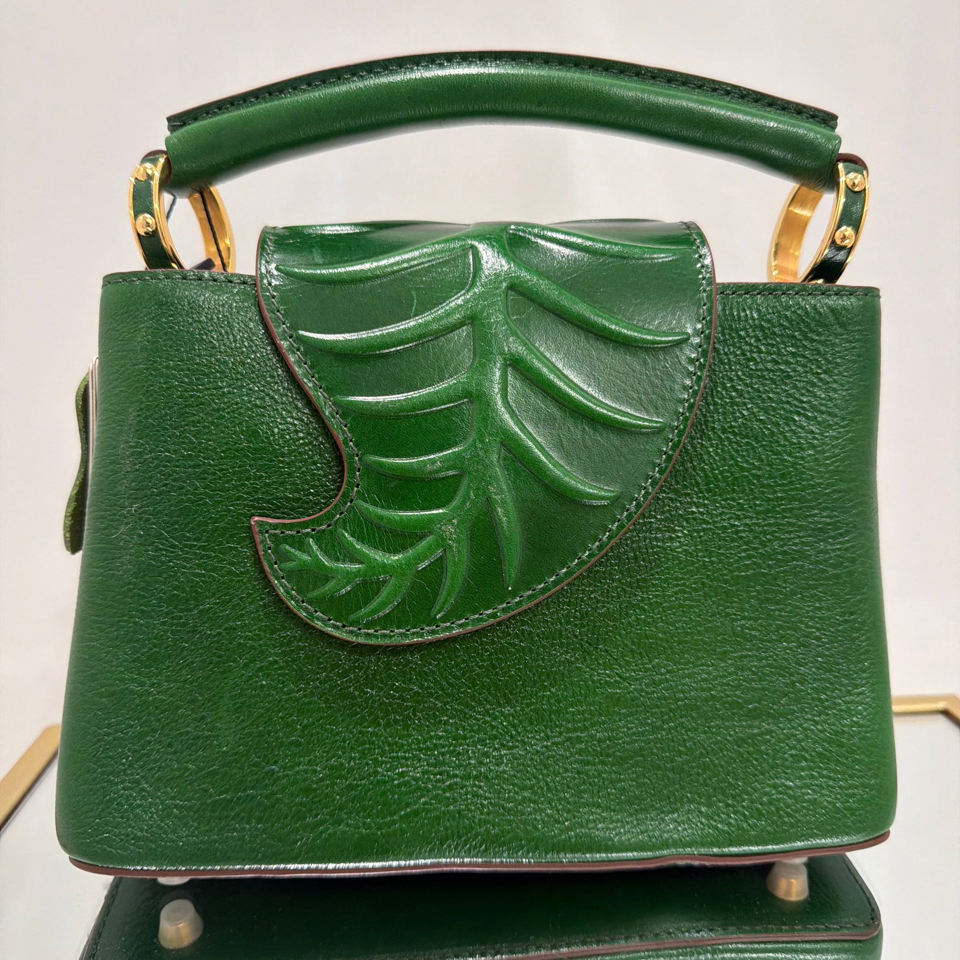 Green handbag with leaf design on a light gray background