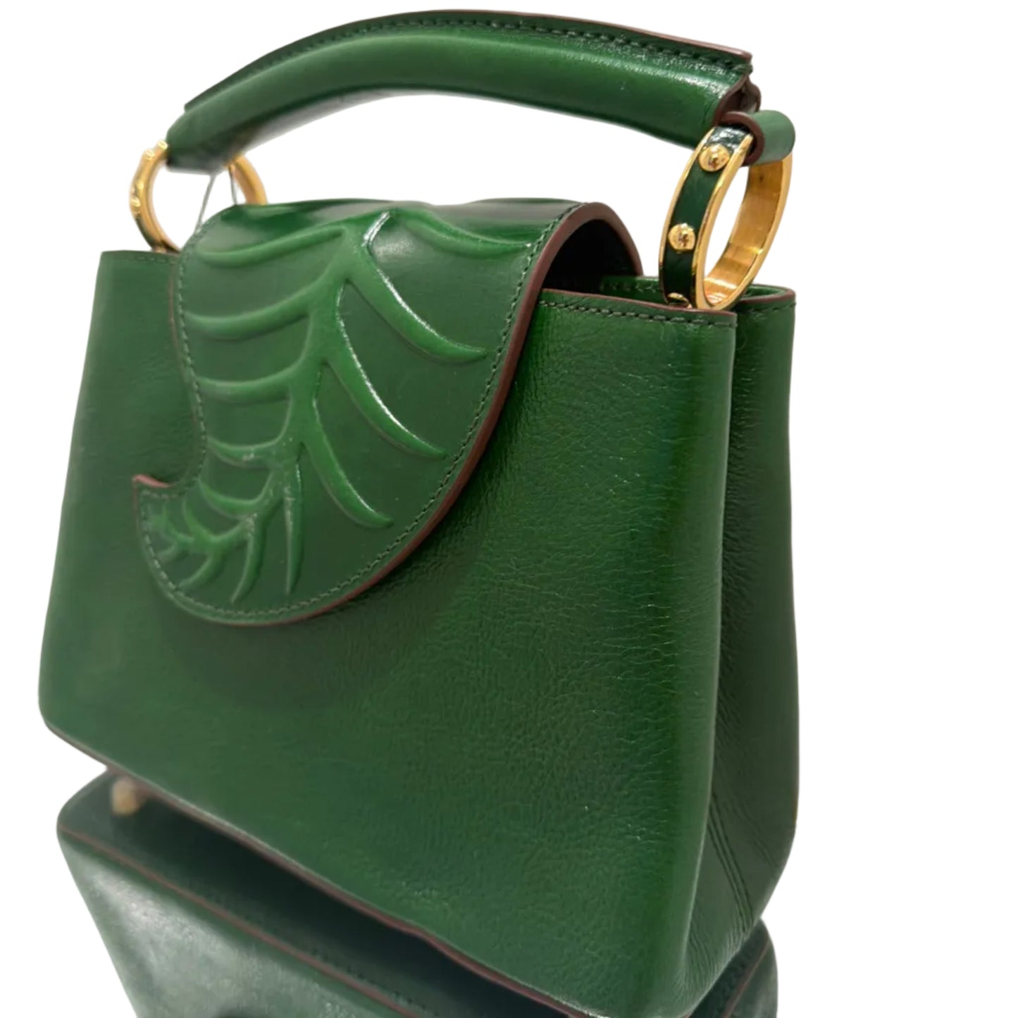 Green handbag with leaf design and gold accents on a white background