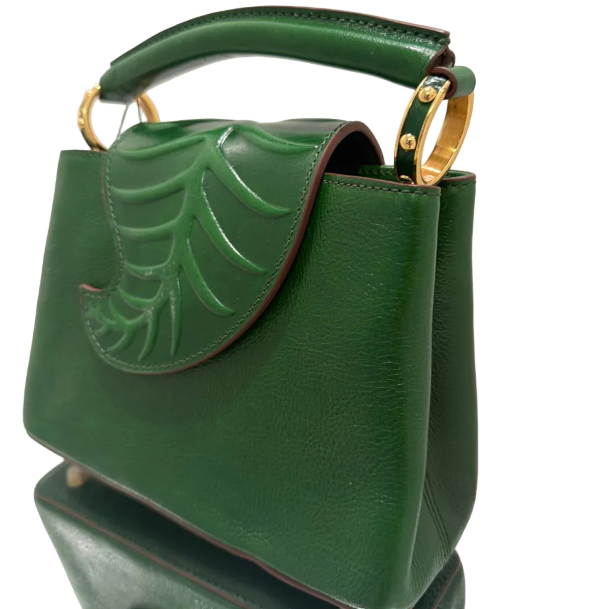 Green handbag with leaf design and gold accents on a white background