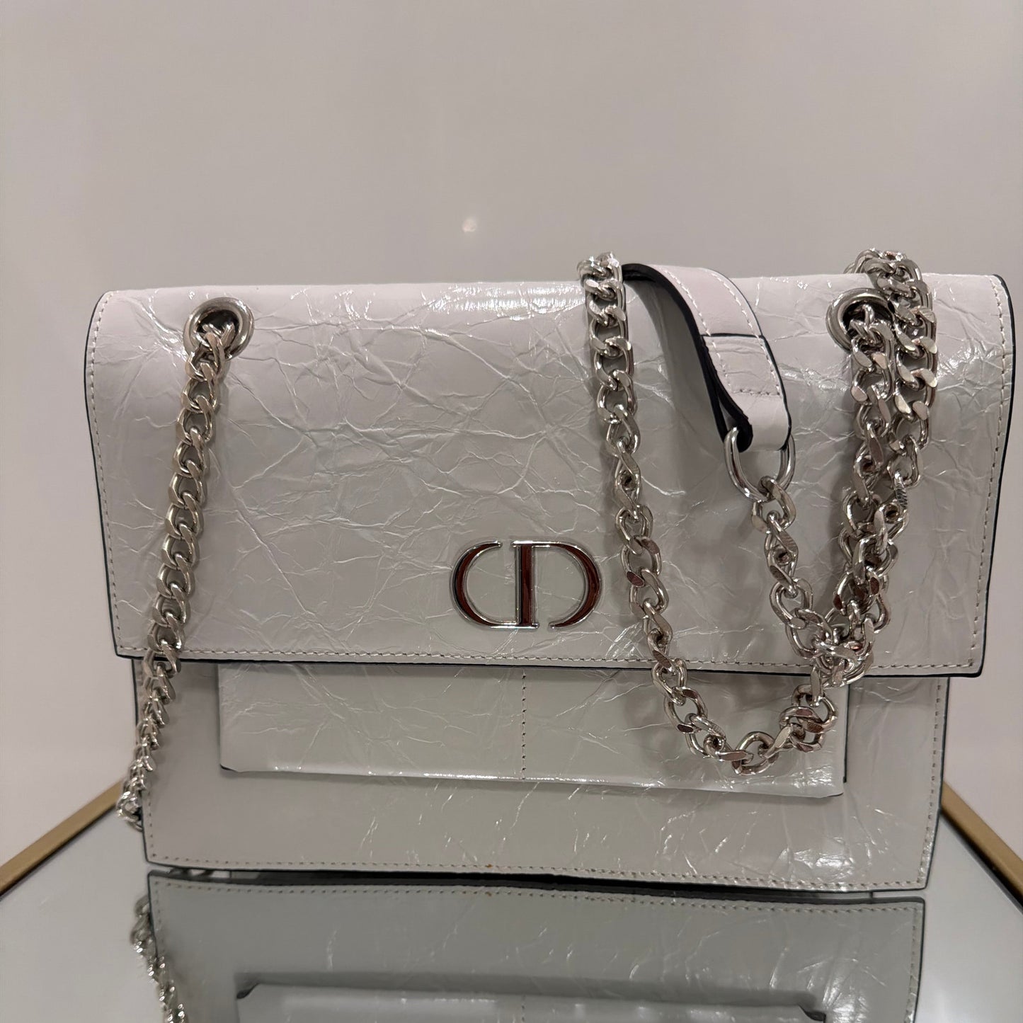 White textured wallet with chain strap on a light gray background
