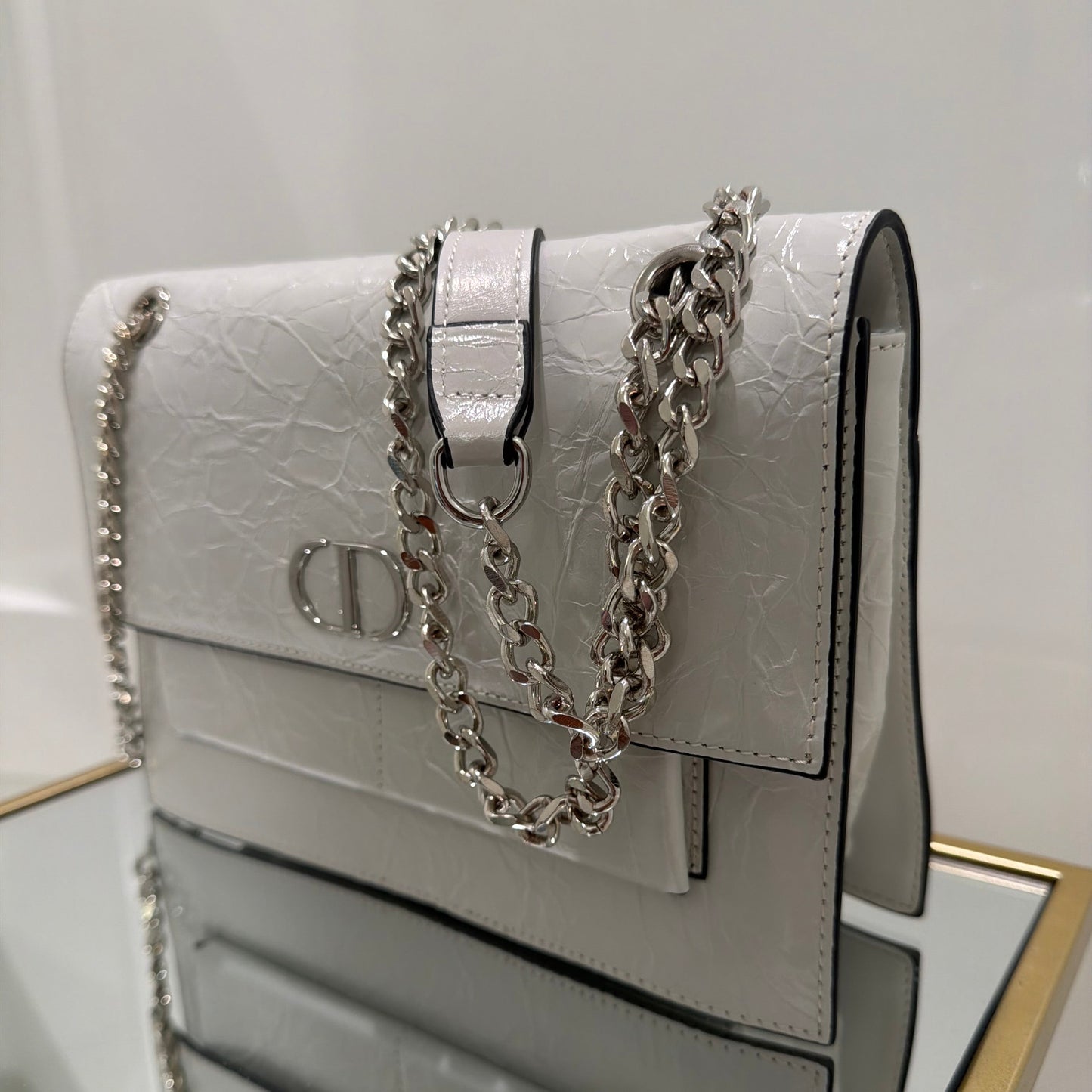 White handbag with a chain detail on a white background
