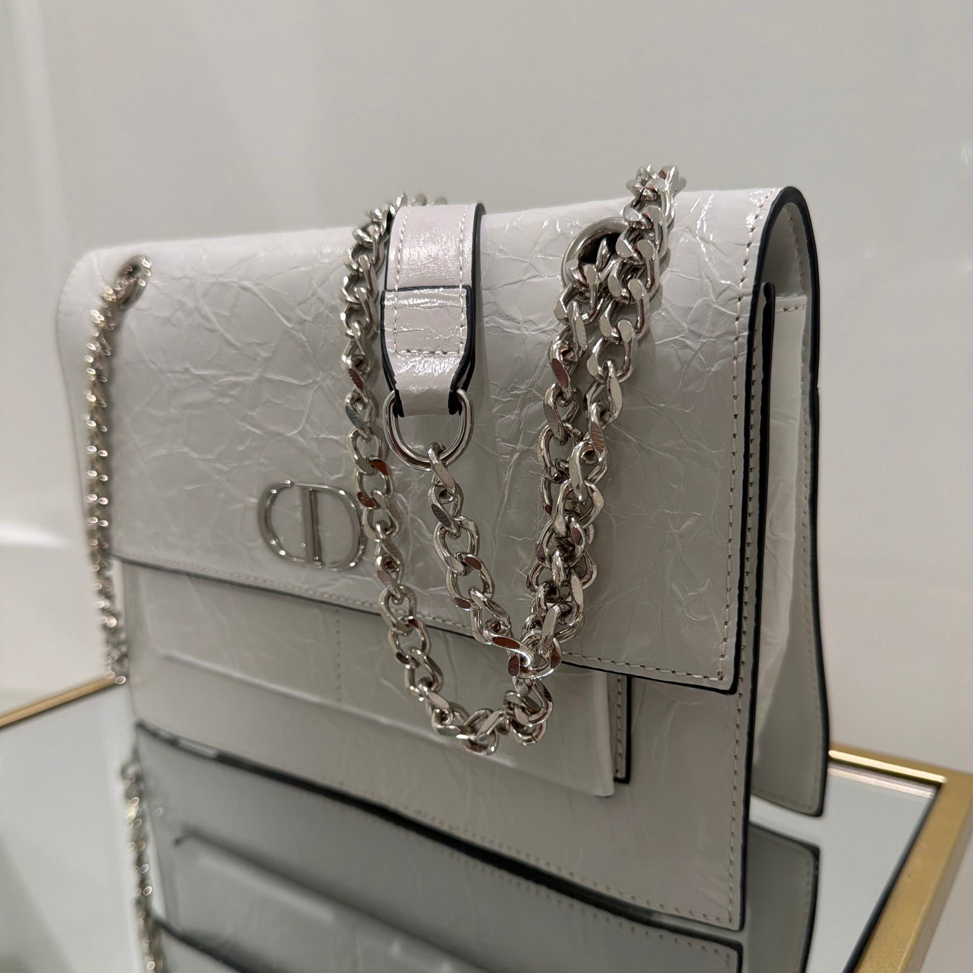 White handbag with a chain detail on a white background