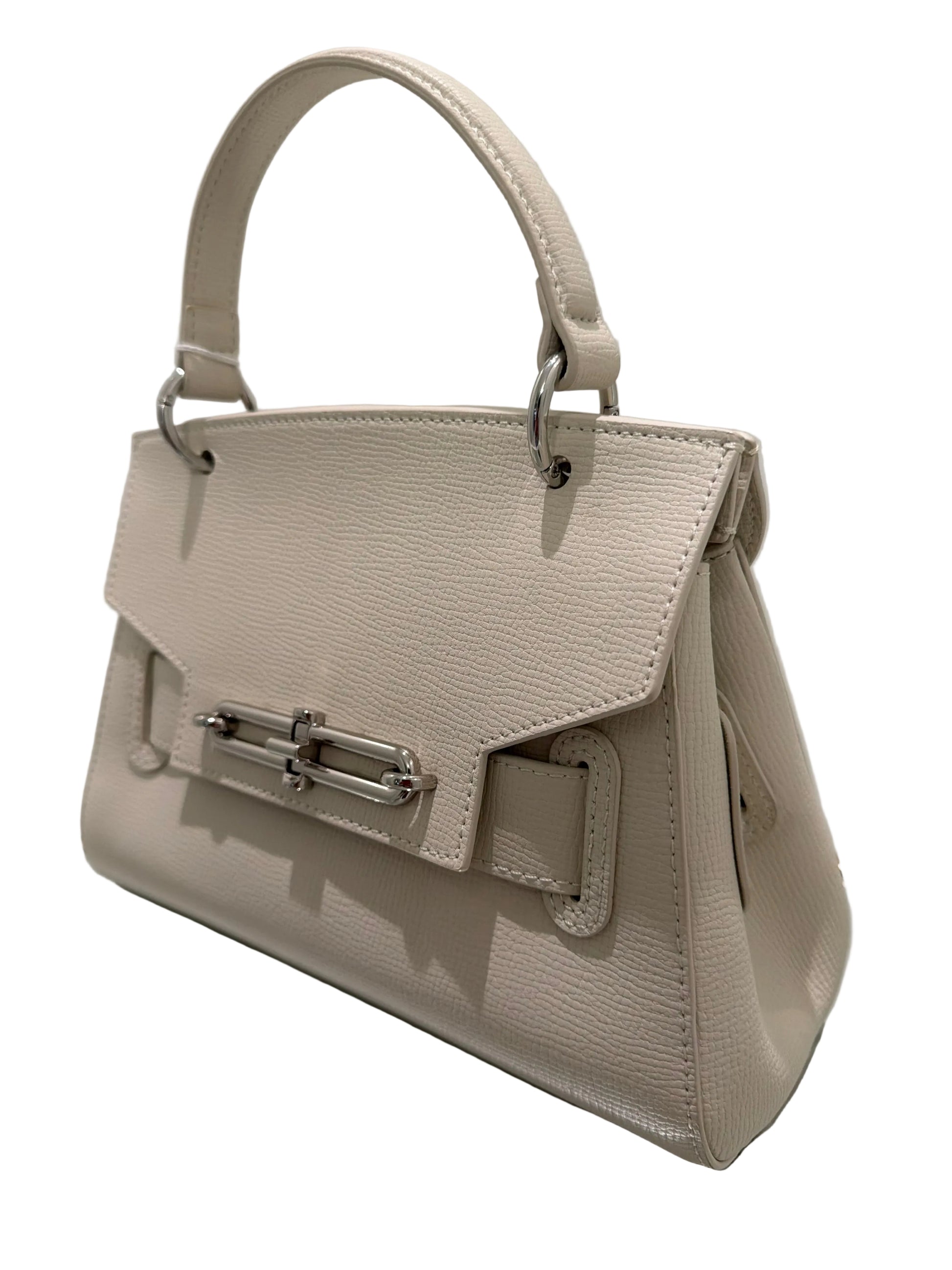 Beige handbag with a metallic clasp on a reflective surface