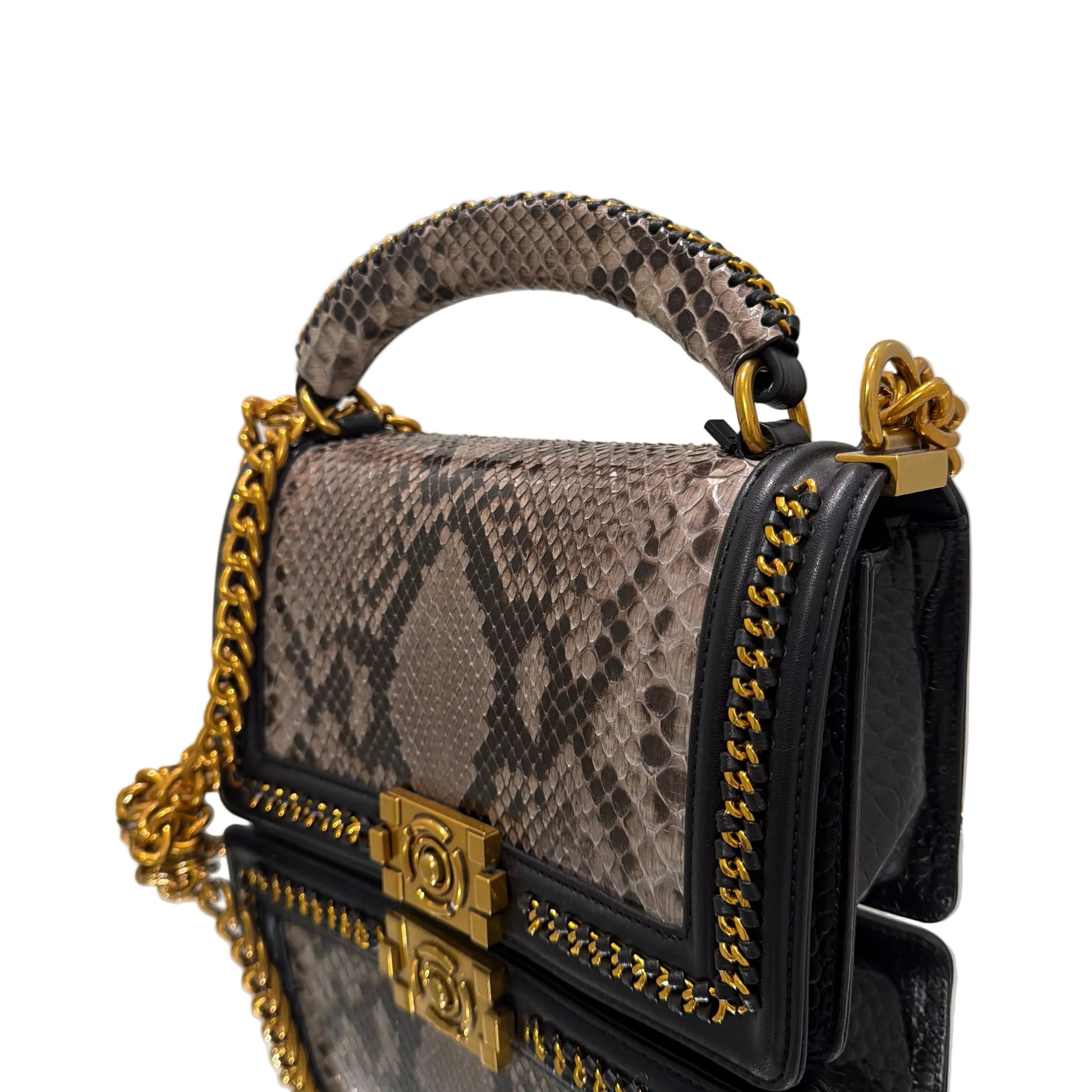 Designer handbag with snake print handle and gold chain detail on a white background